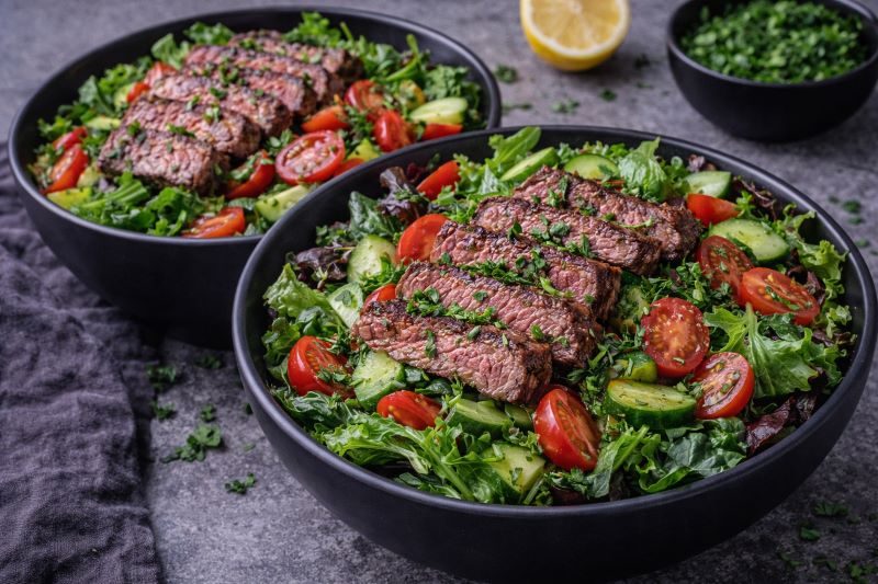 steak salad bowls with sliced steak greens tomatoes and cucumber